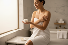 Beautiful woman using body butter after bathing - unlabeled bottles